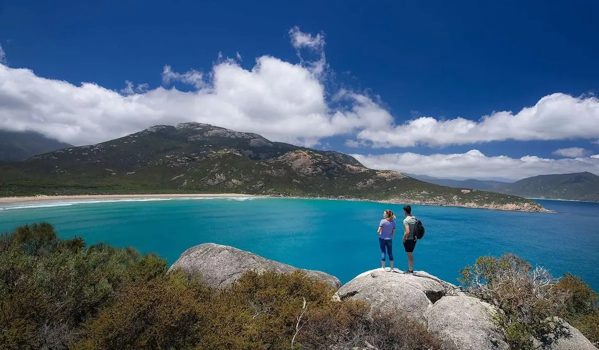 Two walkers on granite boulders looking over a bay at Wilsons Promontory