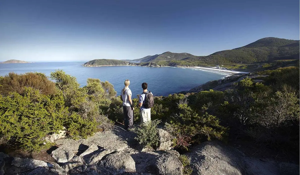 Hikers at a granite summit looking across bays and islands at Wilsons Promontory