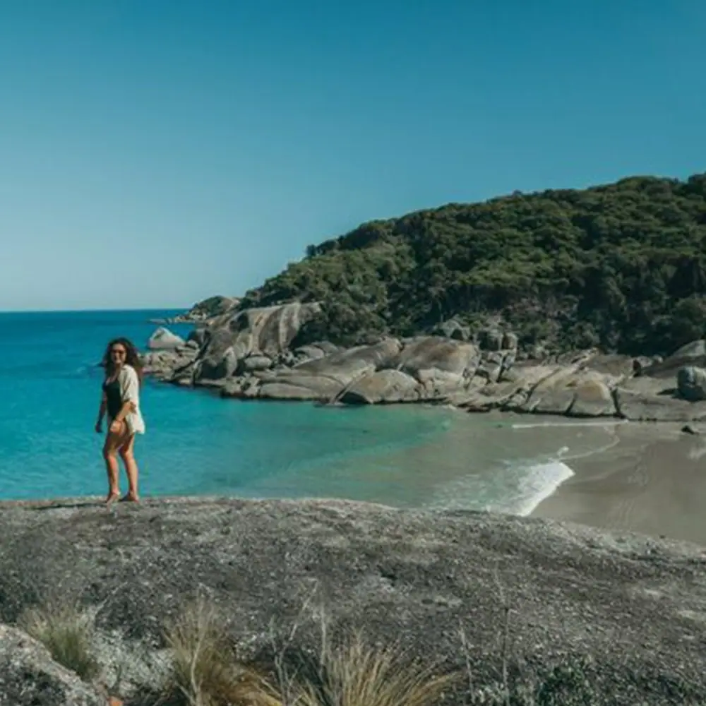 A swimmer on the rocks beside clear water at Wilsons Promontory