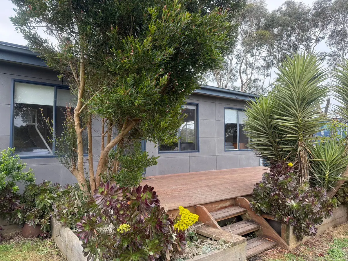The front of Prom Coast Residence, with a timber deck, steps and garden beds