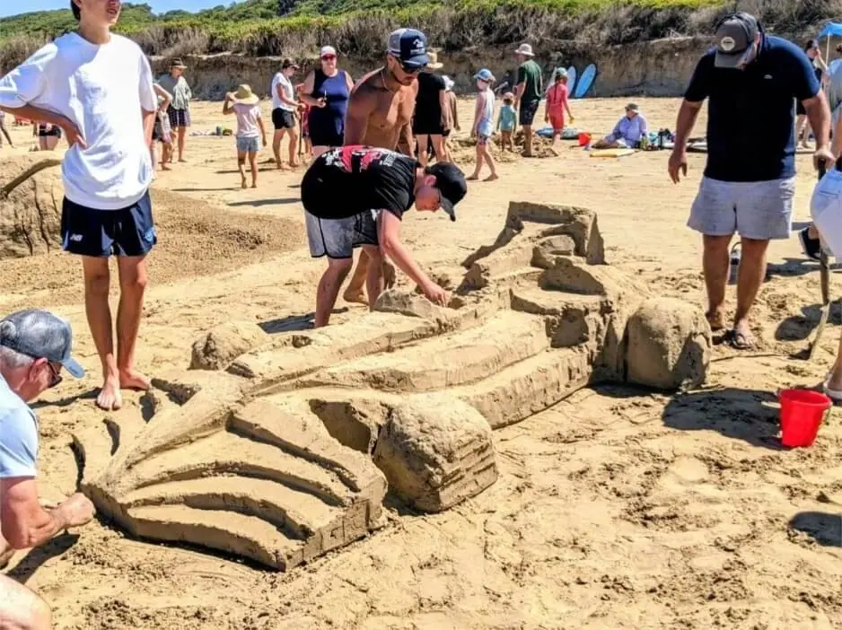 Children and adults building sand sculptures on the beach at Sandy Point